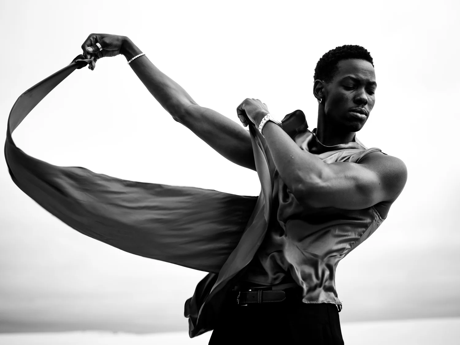 A man in a satin shirt sweeps a long ribbon of fabric through the air.