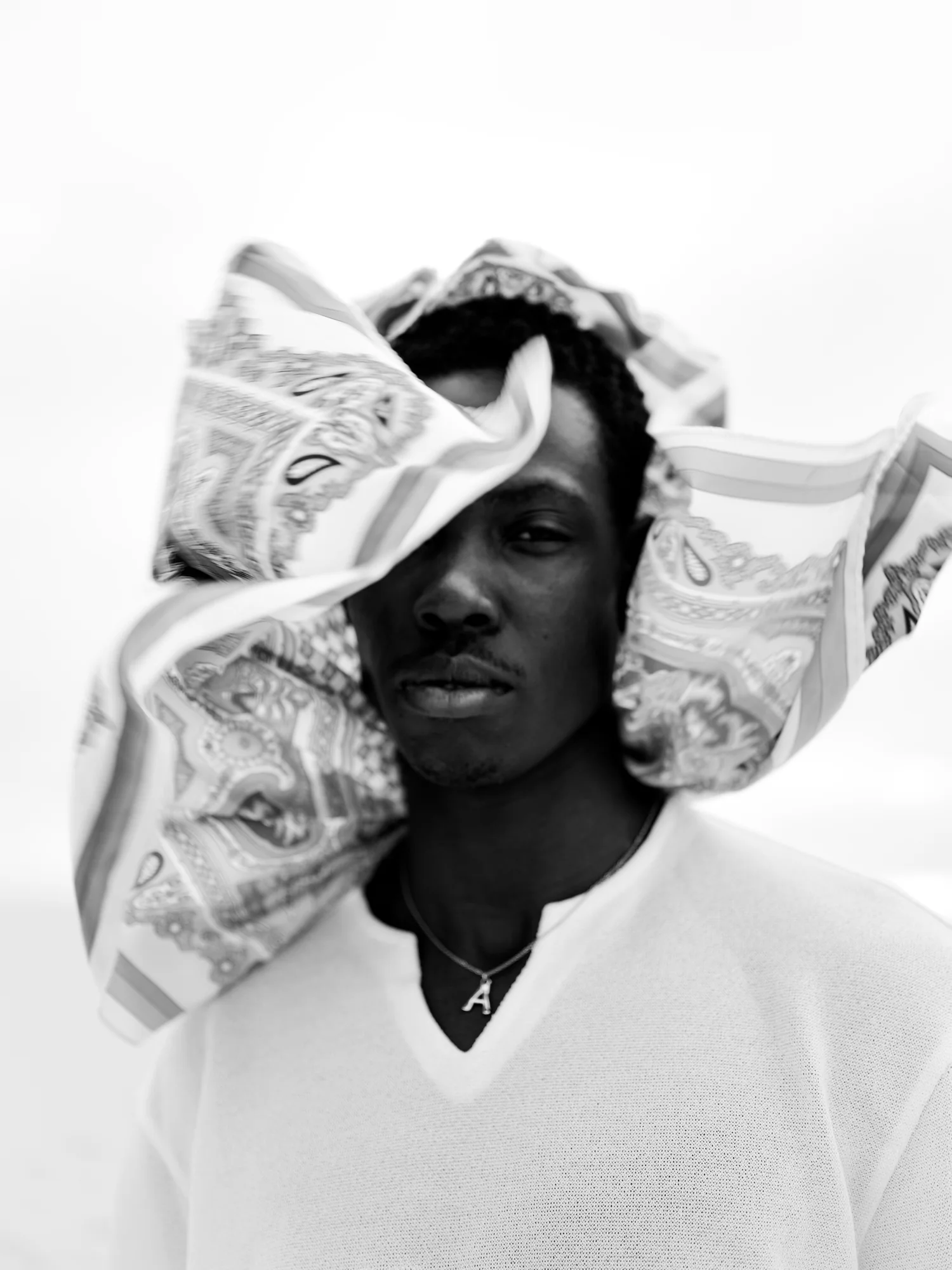 Portrait of a man with a patterned silk scarf billowing around his head.